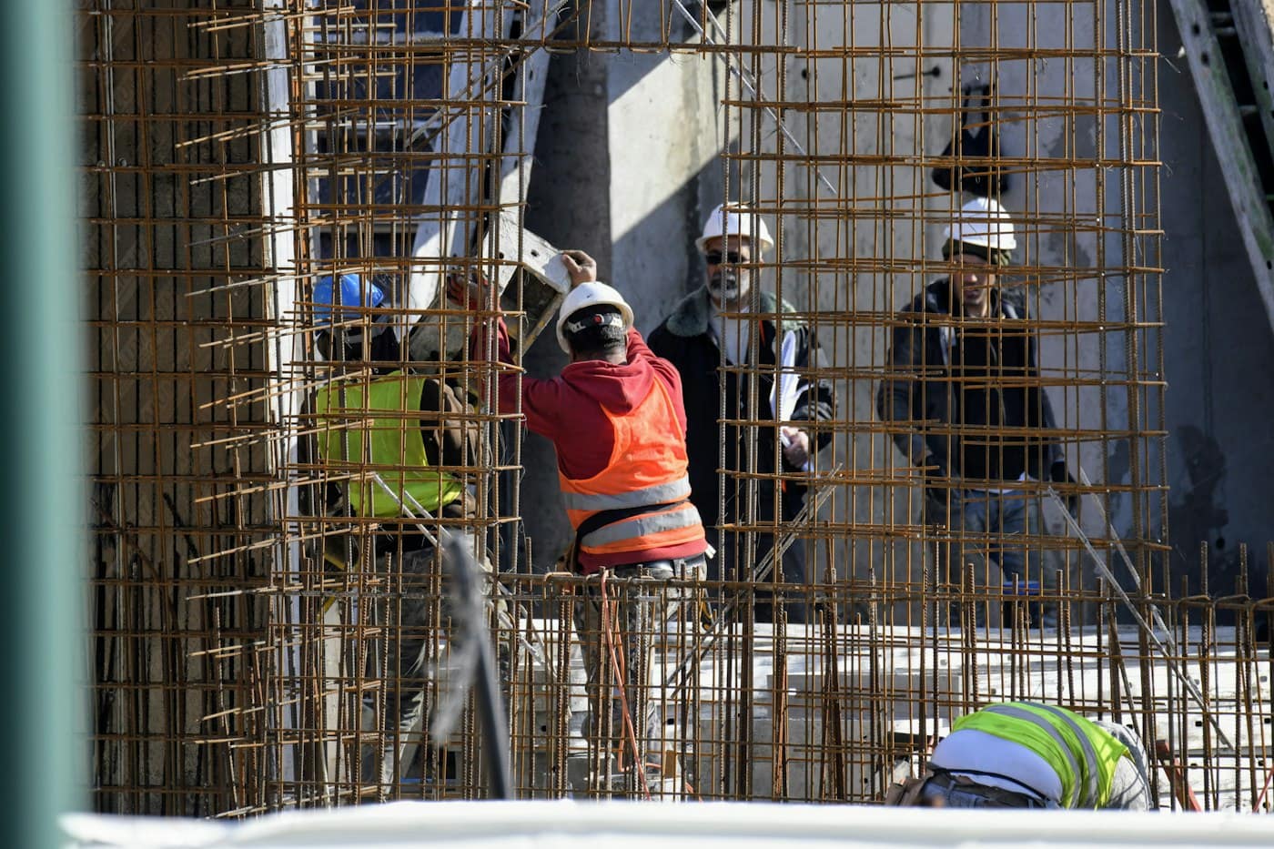 Site crew fixing steel reinforcement on a concrete frame